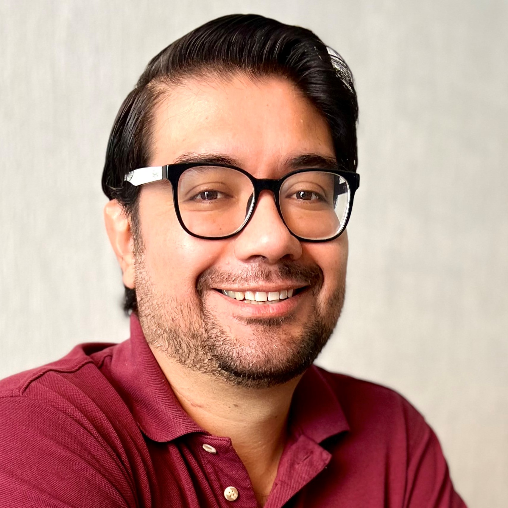 Sergio Nigenda-Morales in a red collared polo shirt and glasses.